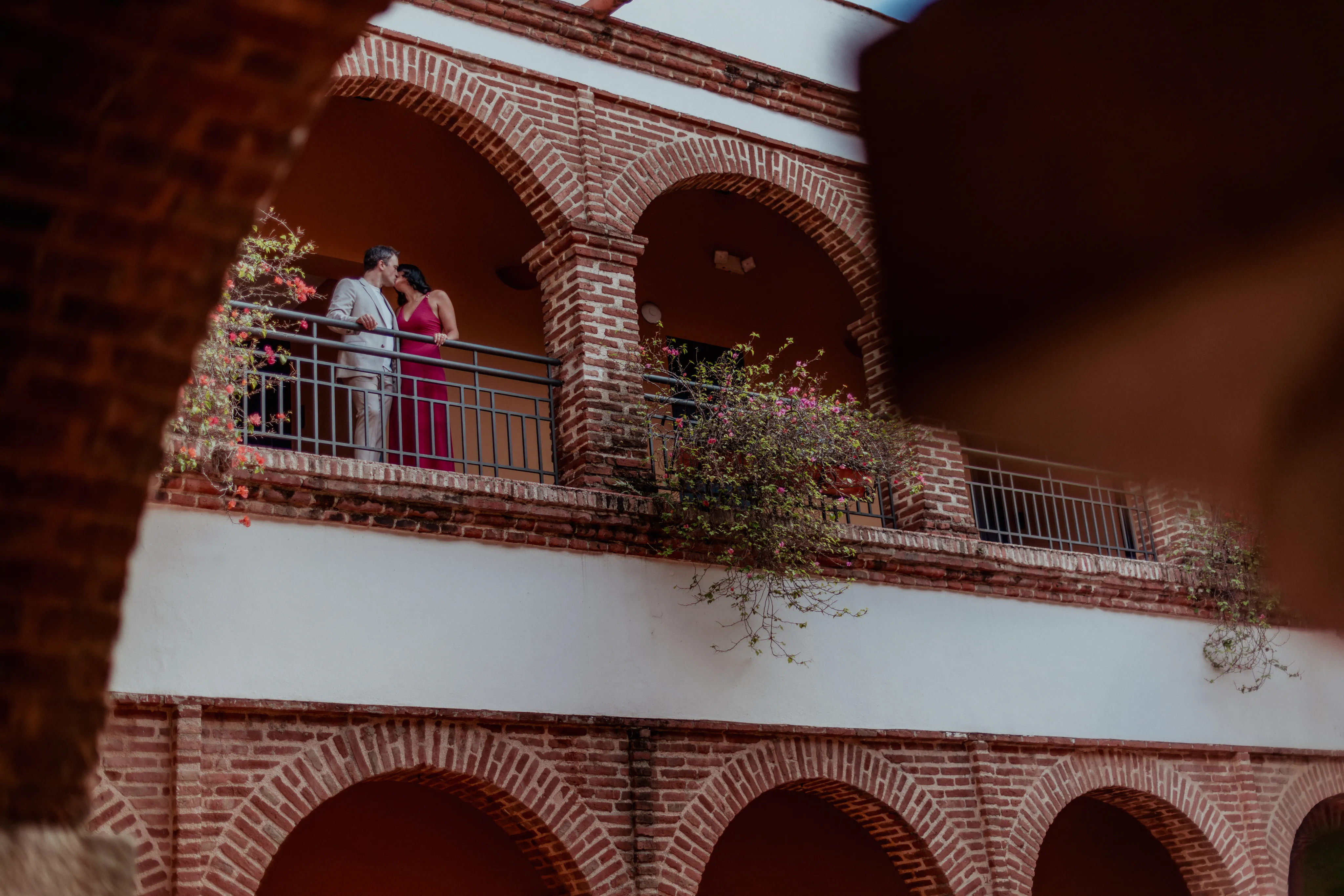 Balcón colonial con pareja en abrazo Pareja en sesión de engagement fotografía en balcón colonial con arcos de ladrillo en Santo Domingo República Dominicana