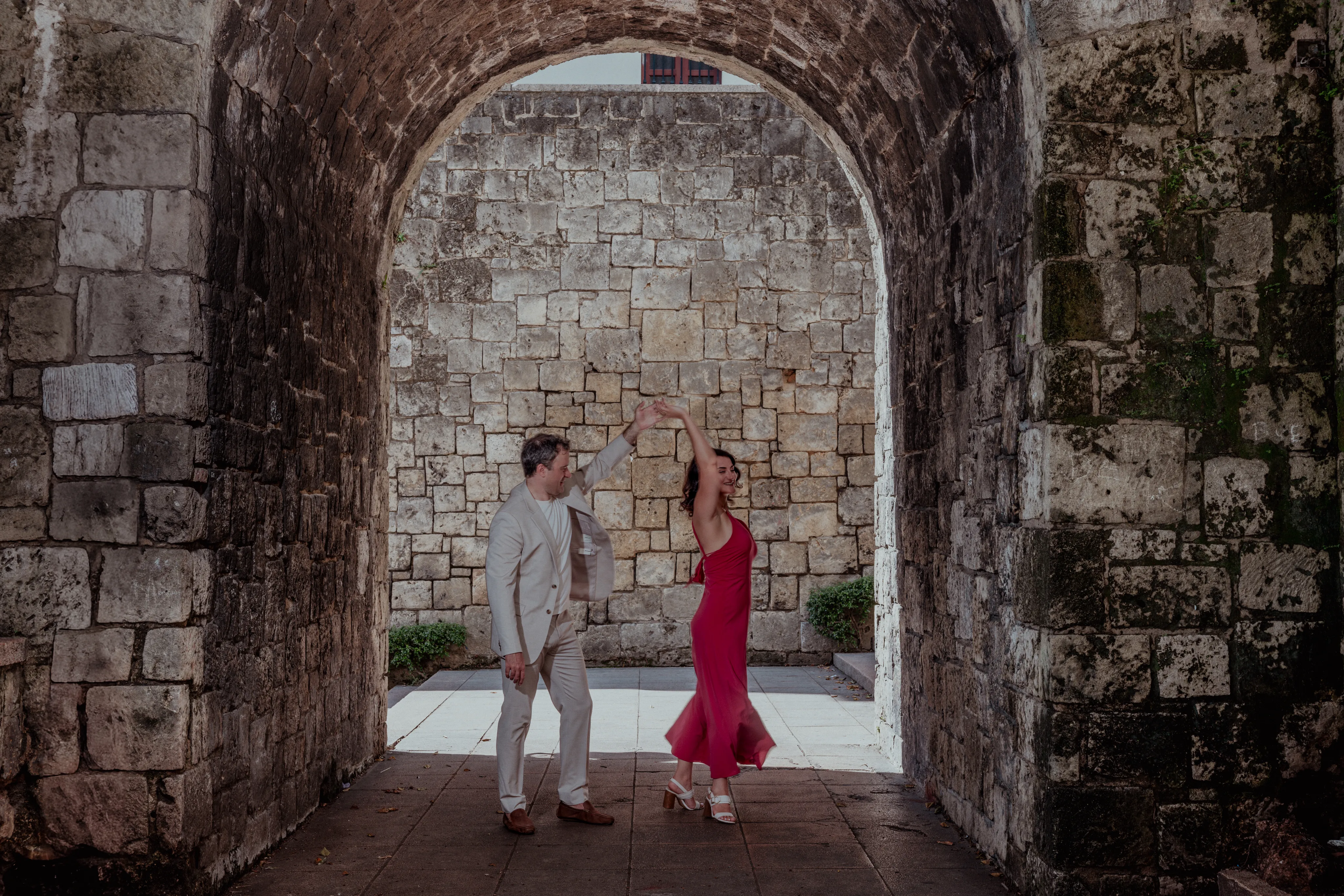 Propuesta de matrimonio bajo el arco colonial Pareja bajo arco de ruinas coloniales en Santo Domingo durante sesión de propuesta matrimonial con luz natural filtrada