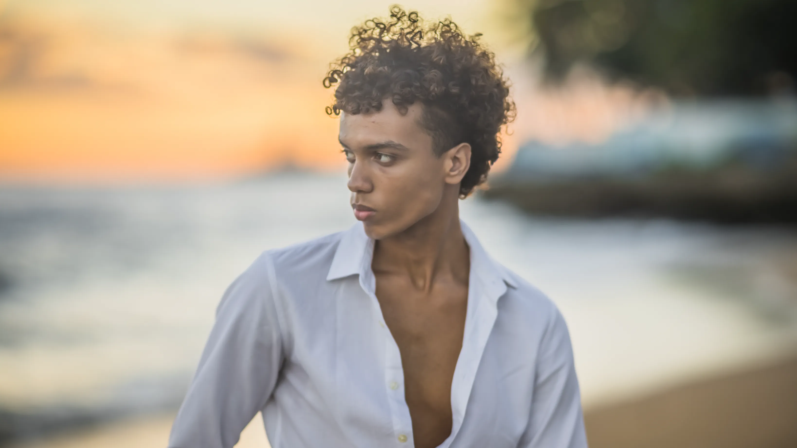 Retrato Dorado en la Playa de Santo Domingo Retrato de lujo en playa al atardecer: joven con camisa blanca frente al océano Atlántico en Santo Domingo